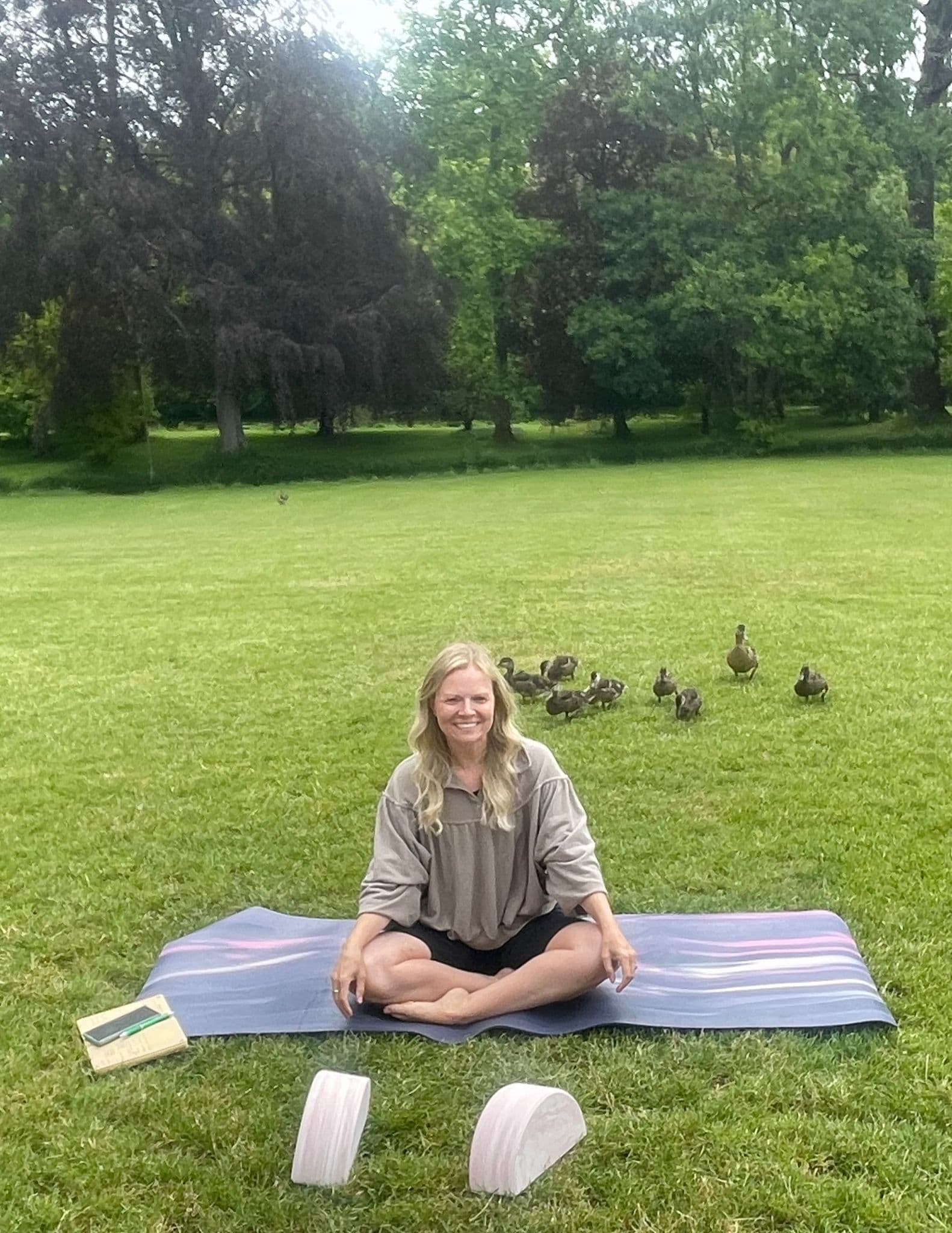 Rachael sitting on her yoga mat outdoors